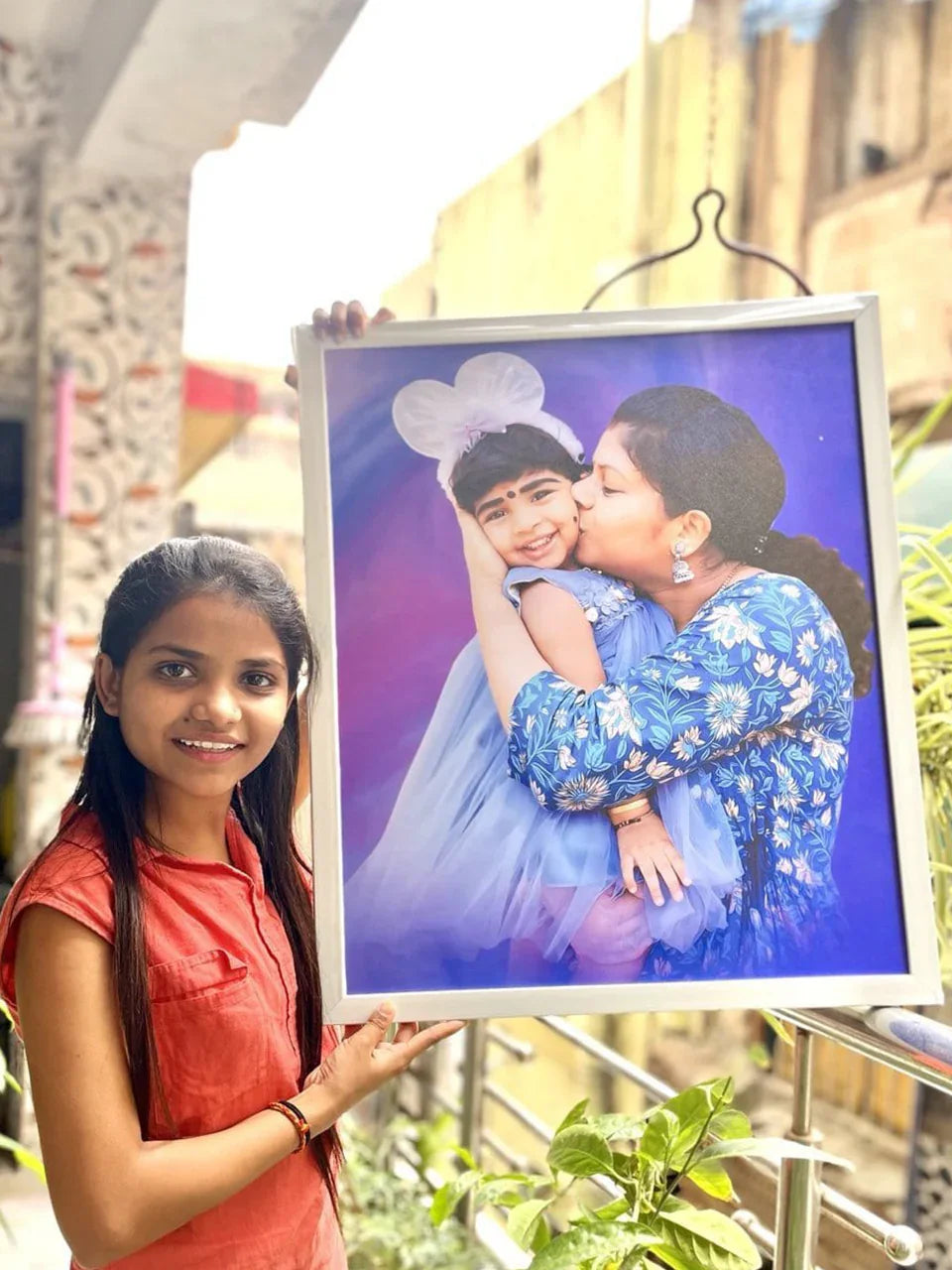 Girl holding framed photo of mother kissing child, perfect personalized gift idea for family memories